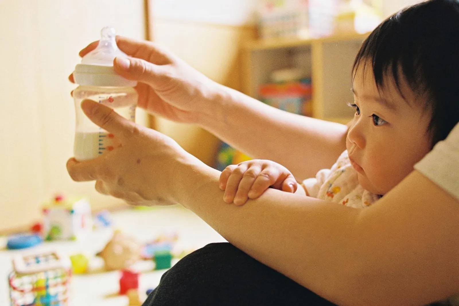 Een leidster geeft een baby de fles